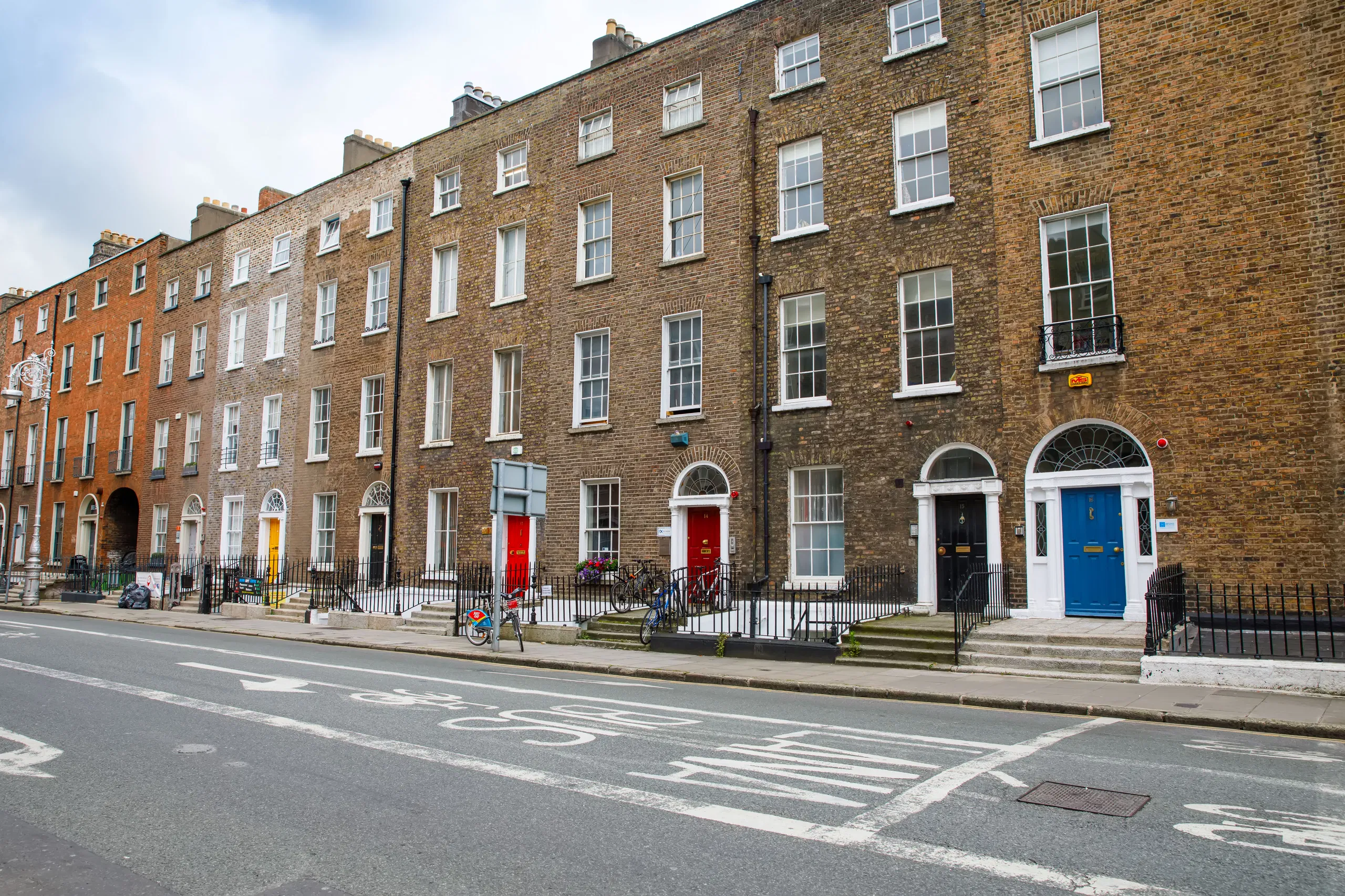 Row of Georgian townhouses with colorful doors on a quiet street in a historic neighborhood.