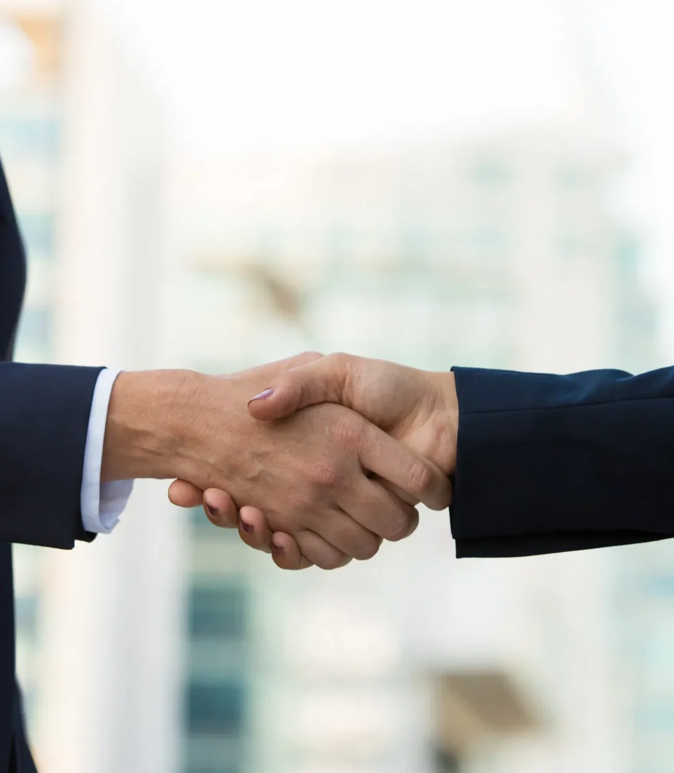 Business handshake between two professionals in suits, symbolizing partnership and agreement.